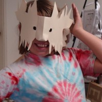 Student with her "Lion" cut & folded paper mask. She then colored it and added fur.